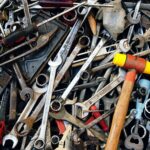 Close-up view of various tools including wrenches and a hammer, providing a cluttered yet organized look.